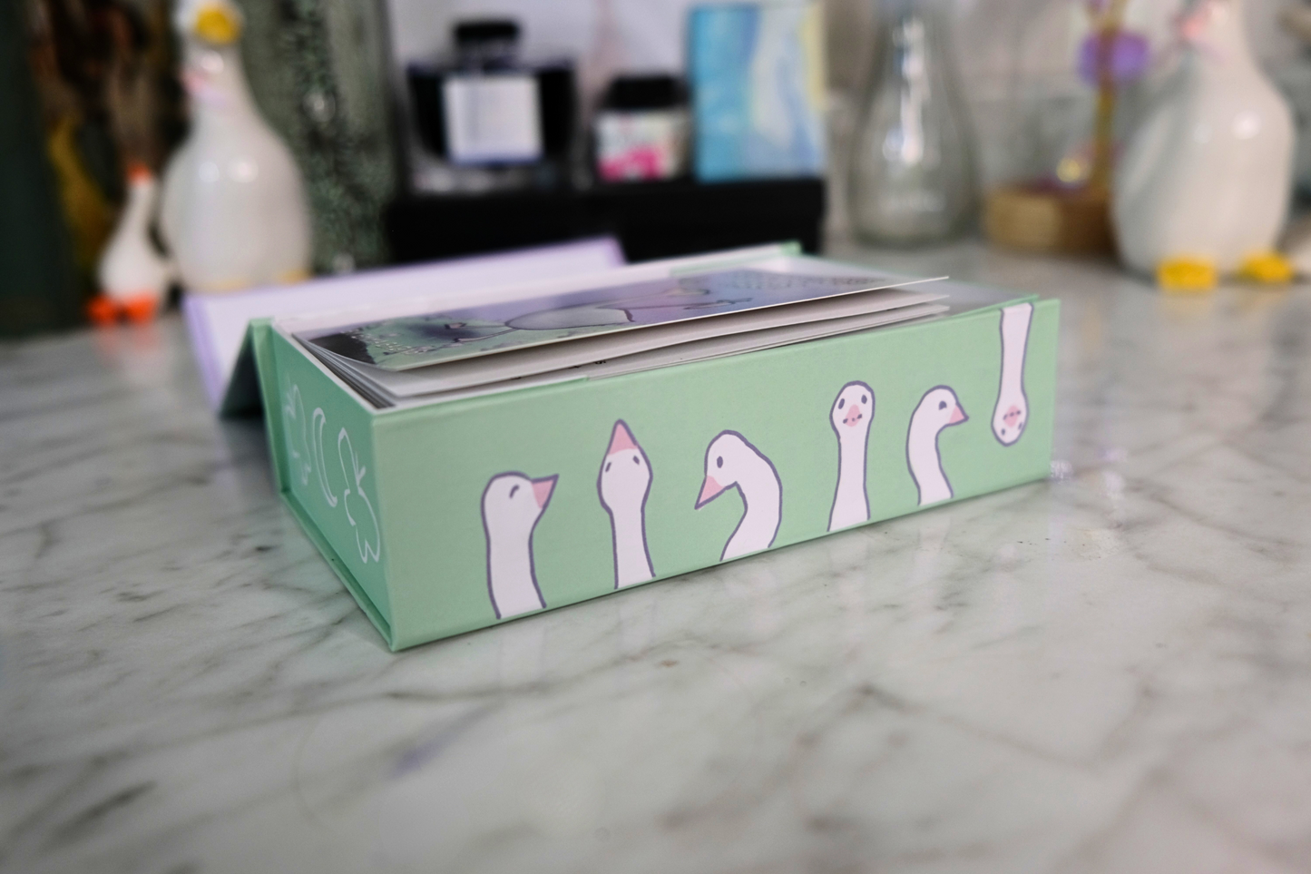 Green box with cartoon goose designs on a marble surface