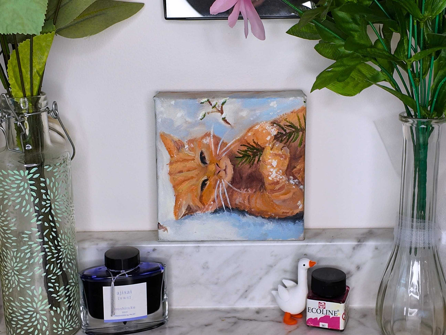 Decorative shelf with a painting of a cat, vases, and small figurines.
