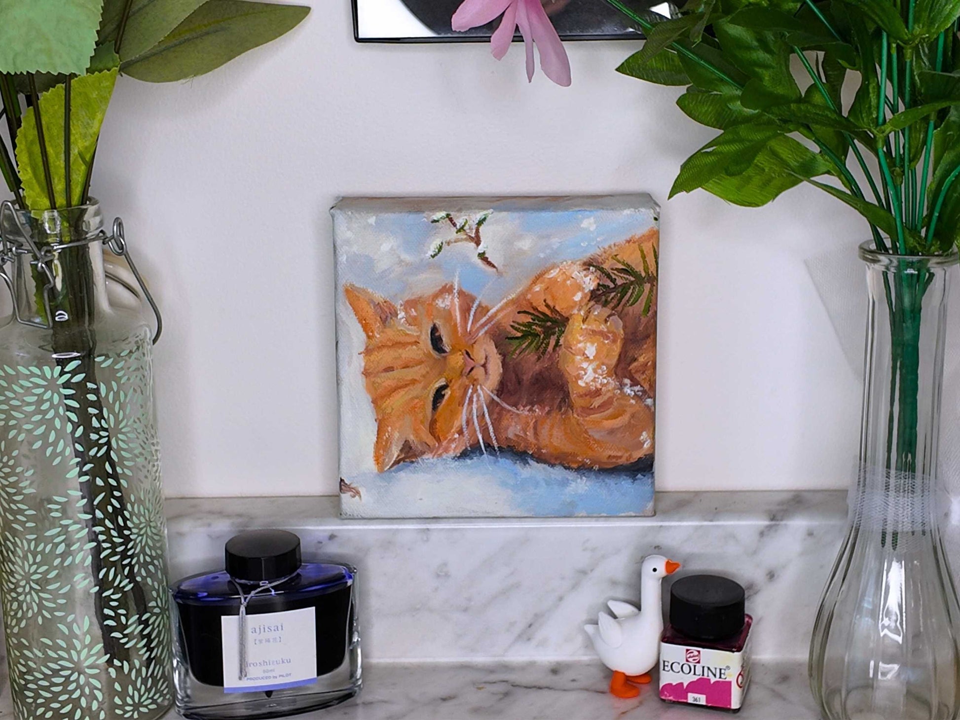 Decorative shelf with a painting of a cat, vases, and small figurines.