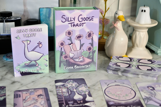 Silly Goose Tarot cards by Emma Baginsky with tarot cards and Goose figurines on a surface.